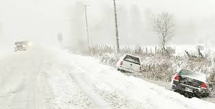 A car pulled over to the side of the road during the snow storm.