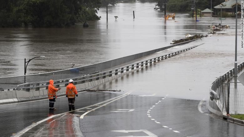 Traffic controllers stand at the Hawkesbury River Bridge submerged by floodwaters in Windsor, New South Wales, Australia, on Monday, March 22, 2021. Western Sydney and the NSW Mid-North coast are bearing the brunt of the relentless downpour that has caused the Warragamba Dam, Sydney???s primary source of water, to overflow for the first time in five years, and caused severe damage to property and roads. Photographer: Brent Lewin/Bloomberg
