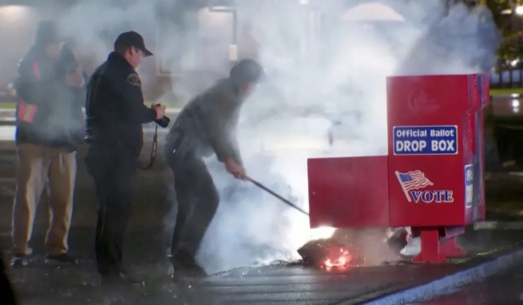 First responders pull out burning ballots from a ballot box.